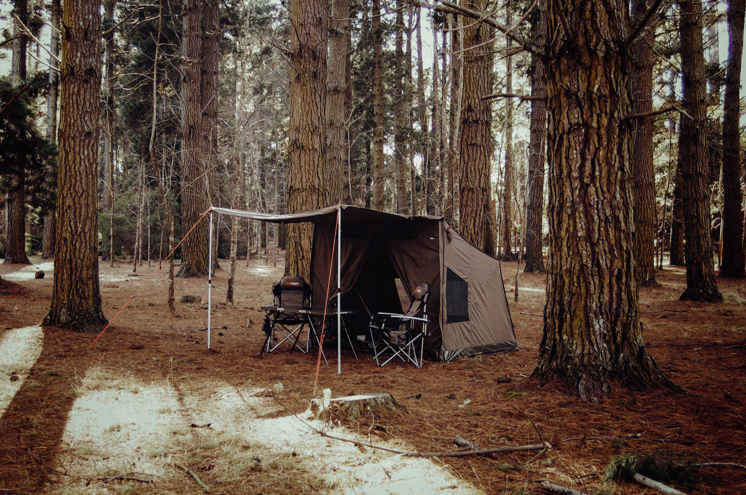 Oztent RV3 in forest with Chairs and Table under the Awning.
